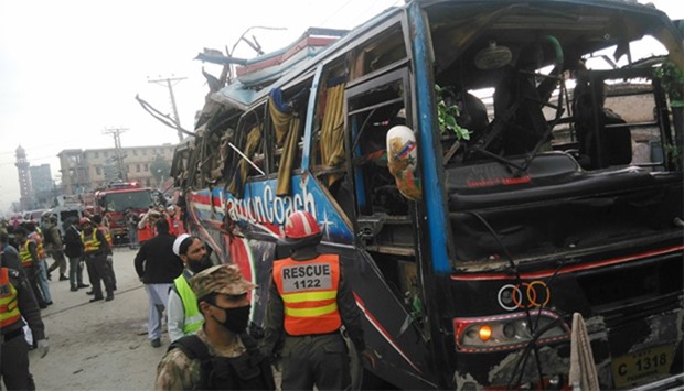 Pakistani security officials search the damaged bus after bomb blast in Peshawar