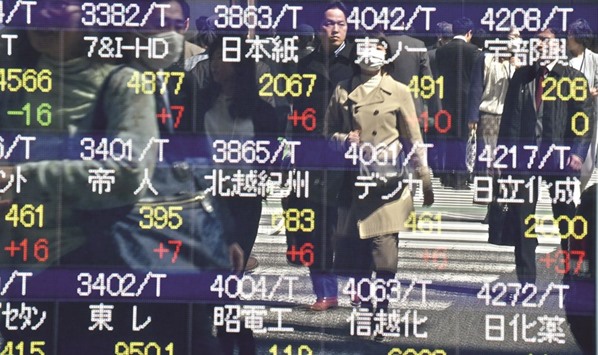 Pedestrians are reflected on an electronic quotation board displaying the Nikkei key index in Tokyo. Tokyo shares succumbed to late selling to end 0.2% down yesterday after the Federal Reserve lowered its outlook for further US interest rate hikes.