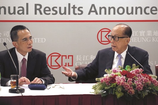 Hong Kong tycoon Li Ka-shing (right) talks to his son Victor during a news conference in Hong Kong. CK Hutchison Holdings, the ports-to-telecoms arm of Asiau2019s richest man, said it may sell a stake in its UK phone carrier Three to help fund its proposed $15bn takeover of rival operator O2 UK.