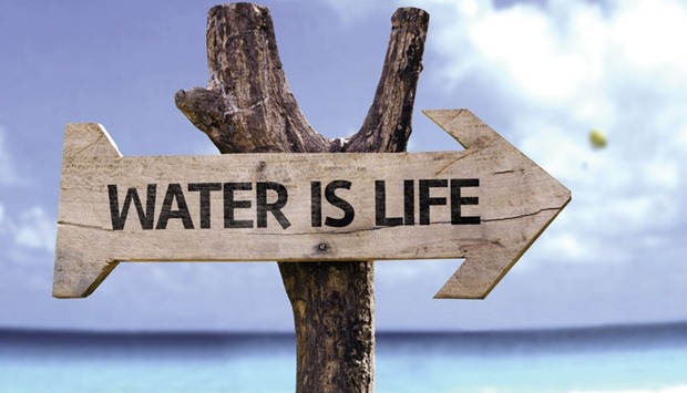 Water is Life wooden sign with a beach on background.