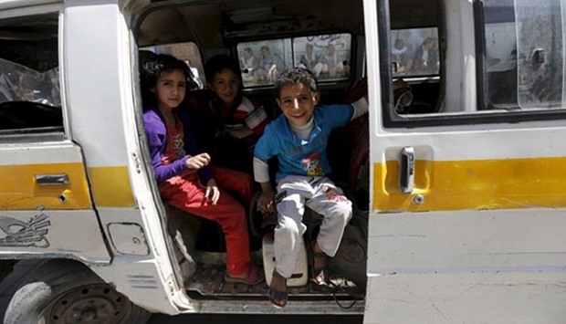 Children wait in a van outside a food distribution centre for poor families in Sanaa
