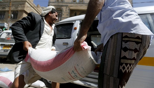 People carry a sack of wheat to a van outside a food distribution center for poor families in Yemen capital Sanaa. Reuters