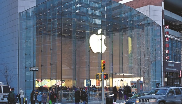Pedestrians pass in front of an Apple store in New York. Apple chief Tim Cook will present a smaller iPhone tomorrow, seeking to entice holdouts to upgrade to a new smartphone even if they donu2019t want a larger device.