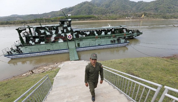 A Laotian soldier walks up a stairway in front of an army patrol boat on the Mekong river port of Mouang Mom on the Laos side of the Golden Triangle, the border between Laos, Myanmar and Thailand.
