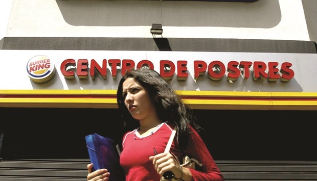 A woman walks past a Burger King restaurant in Caracas, Venezuela (file). Mubadala got a stake in Restaurant Brands International from Eike Batista in 2013 for $300mn. The stake in Oakville, Ontario-based Restaurant Brands, the owner of Burger King, has more than doubled to $715mn since acquiring it from Batista.