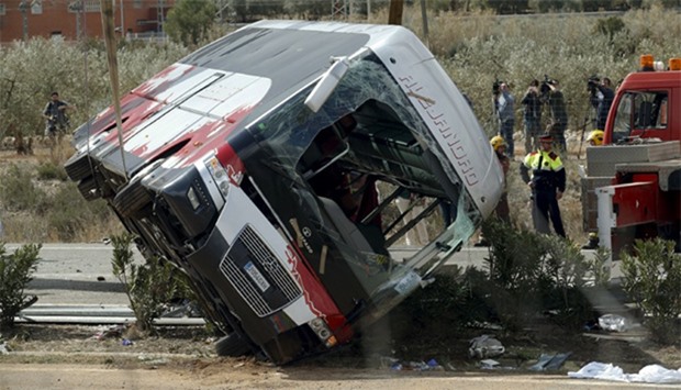 The wreckage of a bus is lifted by a crane after a traffic crash in Freginals, Spain