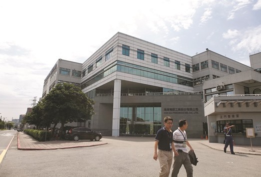 Employees of Hon Hai Precision walk past its headquarters in Taipei. Hon Hai is seeking to reduce the amount it pays for Sharp due to concerns about potential liabilities and future earnings, according to the Yomiuri newspaper.