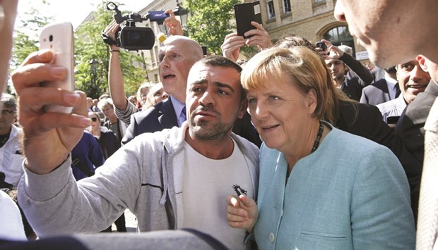 A migrant takes a selfie with Merkel outside a refugee camp near the Federal Office for Migration and Refugees after registration at Berlinu2019s Spandau district, Germany, in this September 10, 2015 file photo. Merkelu2019s government has done an about-turn on its refugee policy such that it has gradually shifted away from its u2018Willkommenskulturu2019, or welcoming culture, the leader of her Bavarian allies told a German newspaper.