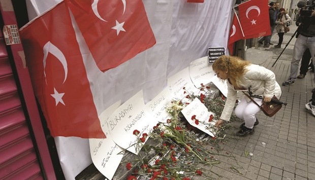 A woman places carnations yesterday at the scene of a suicide bombing at Istiklal street, a major shopping and tourist district, in central Istanbul.