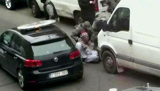 Still image taken from video shows a suspect, his face covered with a scarf, being apprehended by armed Belgian police in Molenbeek, near Brussels, Belgium.