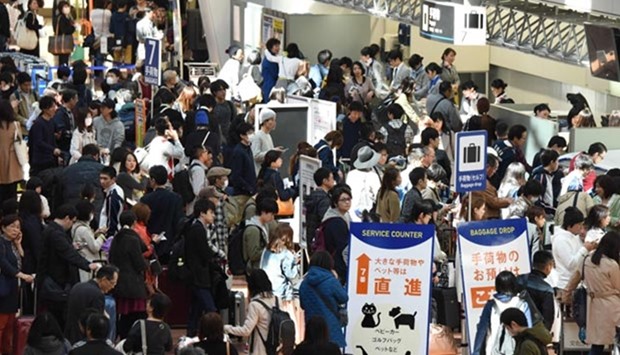 People wait in long queues to check in and get new reservations in front of counters for All Nippon Airways (ANA) on the departures level of Haneda Airport in Tokyo on Tuesday.