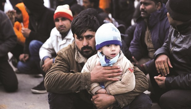 An Afghan migrant holds his son as they wait to be transferred to the Moria registration centre after arriving at the port of Mytilene on the Greek island of Lesbos, following a rescue operation by the Greek Coast Guard at open sea.