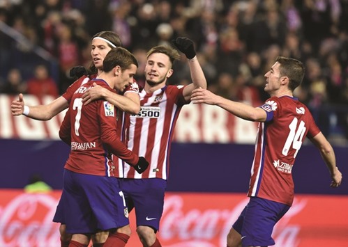 Atletico Madridu2019s French forward Antoine Griezmann (L) is congratulated by his teammates after scoring a penalty during the Spanish league football against Real Sociedad.
