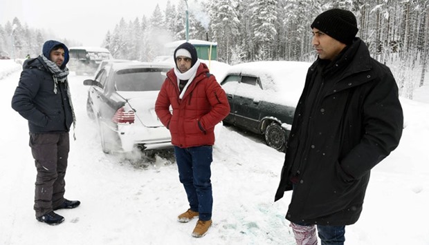 Asylum seekers Rahmatullah (L) and Nazirulhag from Afghanistan and Fida Hussain from Pakistan (R) waiting for permission on the Russian side of the border, near Kuoloyarvi to cross to the Salla border crossing of Finland, January 23, 2016.    Finland and Russia have signed an agreement to close their northern border crossings for migrants, the Finnish government said today.