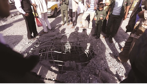 People look at a hole caused by an air strike on a bridge in Yemenu2019s capital Sanaa yesterday.