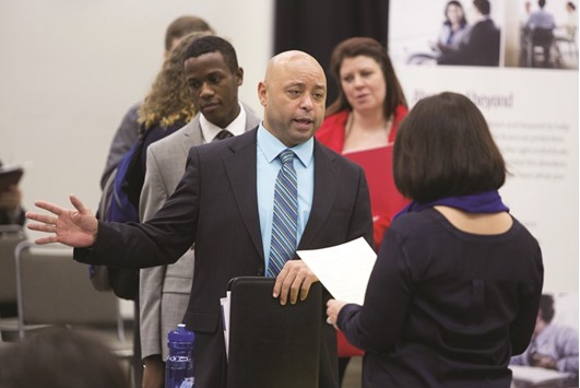 A job seeker speaks with a company representative during a career fair in Seattle. Initial jobless claims increased by 6,000 to 265,000 in the period ended March 19, a Labour Department report showed yesterday.