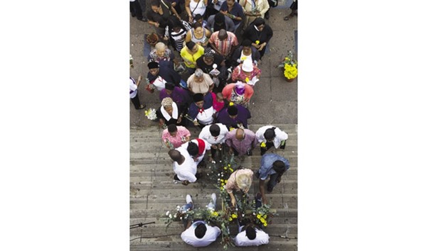 People place flowers on a cross during a silent march celebrating Good Friday in Durban, South Africa.
