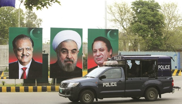 A police vehicle patrols near the portraits of (from left) Pakistanu2019s President Mamnoon Hussain, Iranian President Hassan Rouhani and Pakistanu2019s Prime Minister Nawaz Sharif, displayed along a road during Rouhaniu2019s visit to Islamabad yesterday.