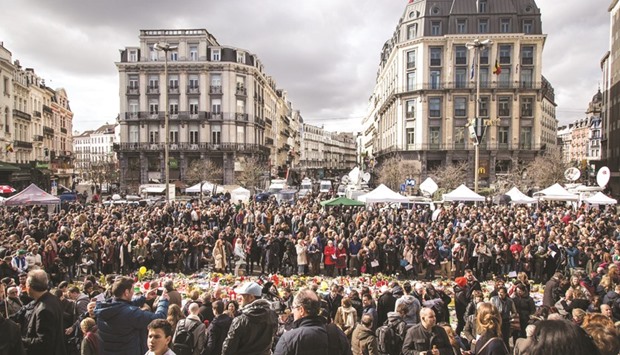People gathering on Place de la Bourse square in Brussels yesterday to pay tribute to the victims of the Brussels terror attacks.  Grieving Belgians held prayers in the rain in a central Brussels square carpeted with flowers and tributes to the 31 killed and 300 injured by the airport and metro suicide blasts on Tuesday.