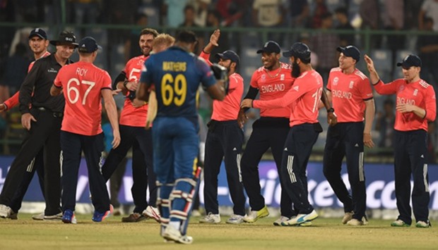 England players celebrate after winning as Sri Lanka's Angelo Mathews (C) walks off the pitch