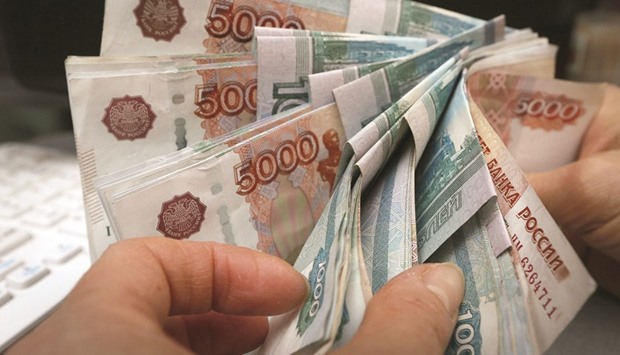 An employee counts rouble banknotes at a shop in Krasnoyarsk, Russia. After posting the second-steepest drop for an emerging market currency in the last quarter of 2015, the rouble has bounced back from its weakest on record in January when crude sank to a 13-year low.