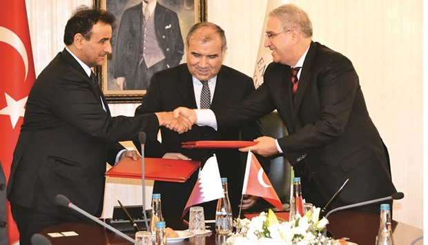 Dr Khalid K al-Hajri and Halil Ali? shake hands after signing the MoU in the presence of Ali R?za Alaboyun.