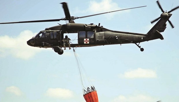 A UH-60 Black Hawk helicopter from the Kansas National Guard carries a water bucket as it prepares to help fight the Anderson Creek wildfire in southern Kansas.