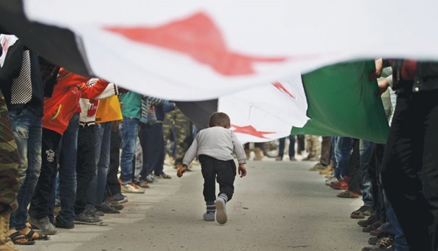 A boy walking under an opposition flag during an anti-government protest in the rebel-controlled area of Maaret al-Numan town in Idlib province, Syria.