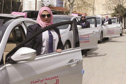 Female taxi drivers pose for a photo in front of their vehicles at Noor Jordan for Transport Taxi Moumayazu2019s (Special Taxi) parking lot in Amman, Jordan. The Jordanian taxi company has launched a new service run only for women, exclusively by women. These three female drivers are among 10 women taxi drivers who will be working as taxi drivers for the first time in Jordan, picking up only female passengers and families. The company chairman Abu al-Haj said they plan to hire another 10 women as drivers, and possibly more if the service expands.