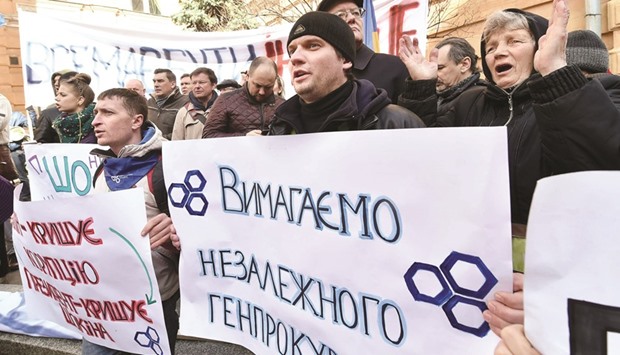 A protester holds a placard reading u2018Demand independent prosecutor generalu2019 during a rally in front of the presidential office in Kiev yesterday.