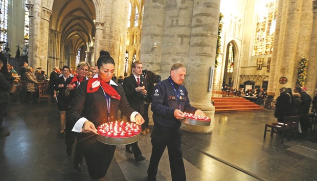Airport personnel and police officers carry candles during a wake for the victims of last weeku2019s terrorist attacks at the Saint Michael and Saint Gudulau2019 Cathedral in Brussels.