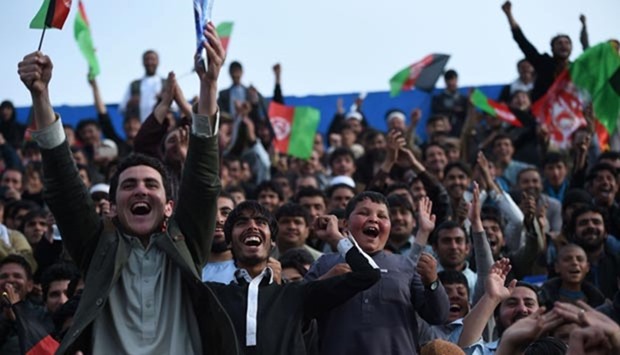 Afghan cricket fans cheer and wave the national flag as they welcome the country's cricket team home at the Cricket Board Stadium in Kabul on Tuesday.