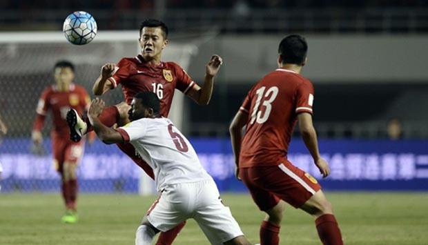 Huang Bowen (left) of China competes for the ball with Abdelaziz Hatim (centre) of Qatar during their 2018 World Cup football qualifying match in Xi'an on Tuesday.