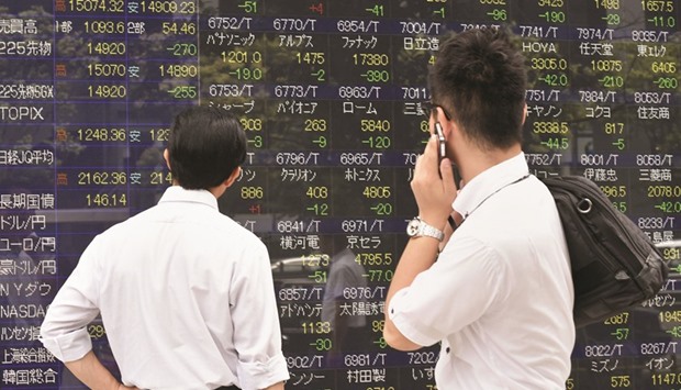 Pedestrians look at a share prices board in Tokyo. The Nikkei 225 closed down 0.2% to 17,103.56 points yesterday.