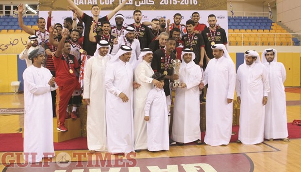 Qatar Basketball Federation President Sheikh Saoud bin Abdulrahman al-Thani presents the Qatar Cup to Al Rayyan captain Yaseen Ismail Musa. At bottom, fans enjoy the action from the stands.