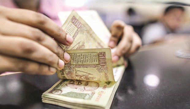 A teller counts Indian rupee notes inside a bank in Mumbai. While the rupee fell 0.4% versus the dollar this year, flows from stock investors turned positive in March amid slower inflation, an improved current account and budgetary discipline.