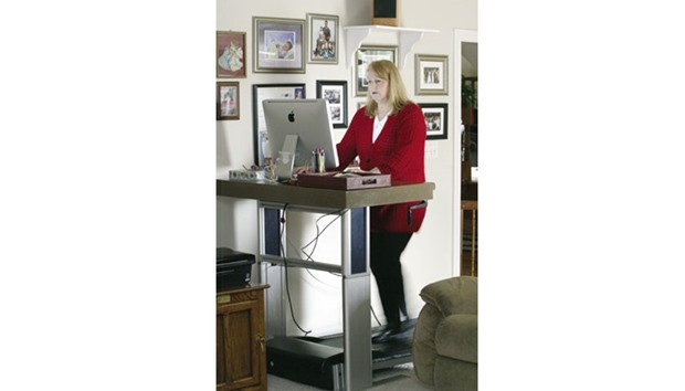 A woman working  at a treadmill desk at home.