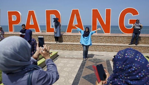 Visitors to the coastline take pictures with the Indian Ocean in the background a day after a 7.8 magnitude quake struck far out at sea in Padang, West Sumatra province.