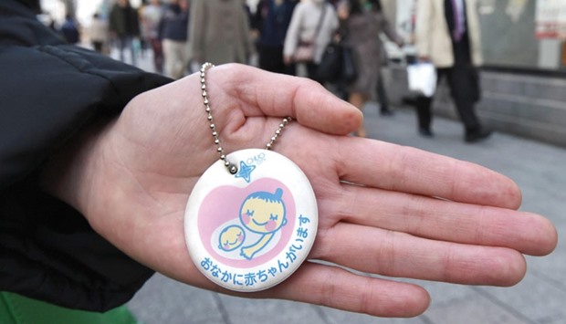 A woman holds a maternity mark on a Tokyo street.