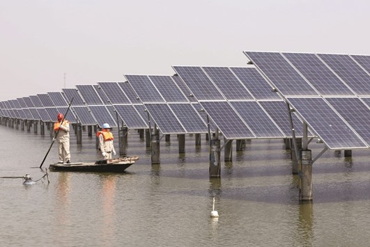 Employees row a boat as they examine solar panel boards at a pond in Lianyungang, Jiangsu province. Global funds are cautiously venturing back into Chinese equities after prices collapsed to 4-1/2-year lows in February, taking advantage of cheaper valuations to buy stocks they believe will benefit from the countryu2019s shift to a consumption-led economy.