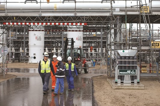Workers pass gas absorber towers as construction continues on the gas cleaning installation at the Boekelermeer storage site, operated by Abu Dhabi National Energy Co (TAQA) and EBN BV, the Dutch state-owned energy company, in Alkmaar, Netherlands in this photo taken on April 29, 2014. TAQA, 75% owned by the government of Abu Dhabi, said it had reduced capex by 52% in 2015 and would cut spending by a further 42% in 2016 to no more than 1.8bn dirhams ($490mn).