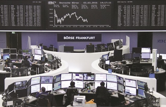 Traders work at their desks in front of the German share price index at the Frankfurt Stock Exchange. The DAX dipped 0.2% at closing yesterday.