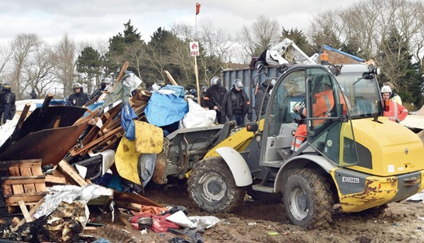 A bulldozer dismantles shelters on February 29 in the u201cJungleu201d migrant camp in the French northern port city of Calais.