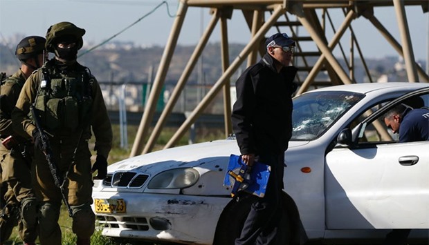 An Israeli soldier inspects a car with its windshield riddled with bullets holes at the scene of a car ramming attack in the Gush Etzion junction