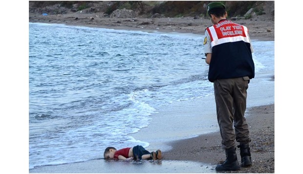 A Turkish police officer standing next to the body of Aylan Kurdi off the shores in Bodrum, southern Turkey, in this file photo taken on September 2, 2015.