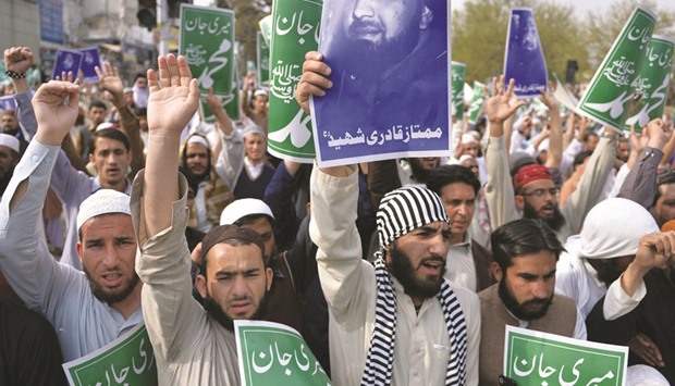 Supporters of different religious parties hold signs and picture of Mumtaz Qadri to condemn his execution during a protest rally in Islamabad yesterday.