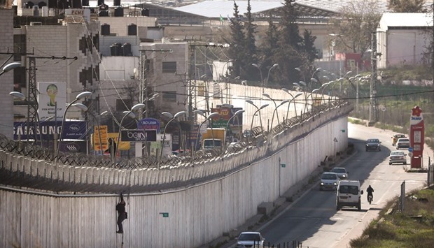 A Palestinian man uses a rope to climb over a section of Israelu2019s controversial separation barrier that separates the West Bank city of Al-Ram from east Jerusalem. Many Palestinians from the West Bank cross into Israel every day in search for work.