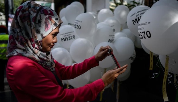 A woman takes pictures of balloons with names of the missing Malaysia Airlines flight MH370 during a memorial event in Kuala Lumpur on Sunday.