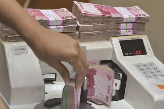 An employee counts Indonesian rupiah banknotes at a money changeru2019s office in Jakarta. The yield on the 10-year 8.375% rupiah notes fell 80 basis points this year through February 11 to a nine-month low of 7.95% before rising to 8.01%.