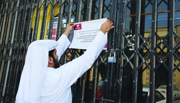 An inspector from the MEC putting up the closure notice outside the company at Al Wakrah